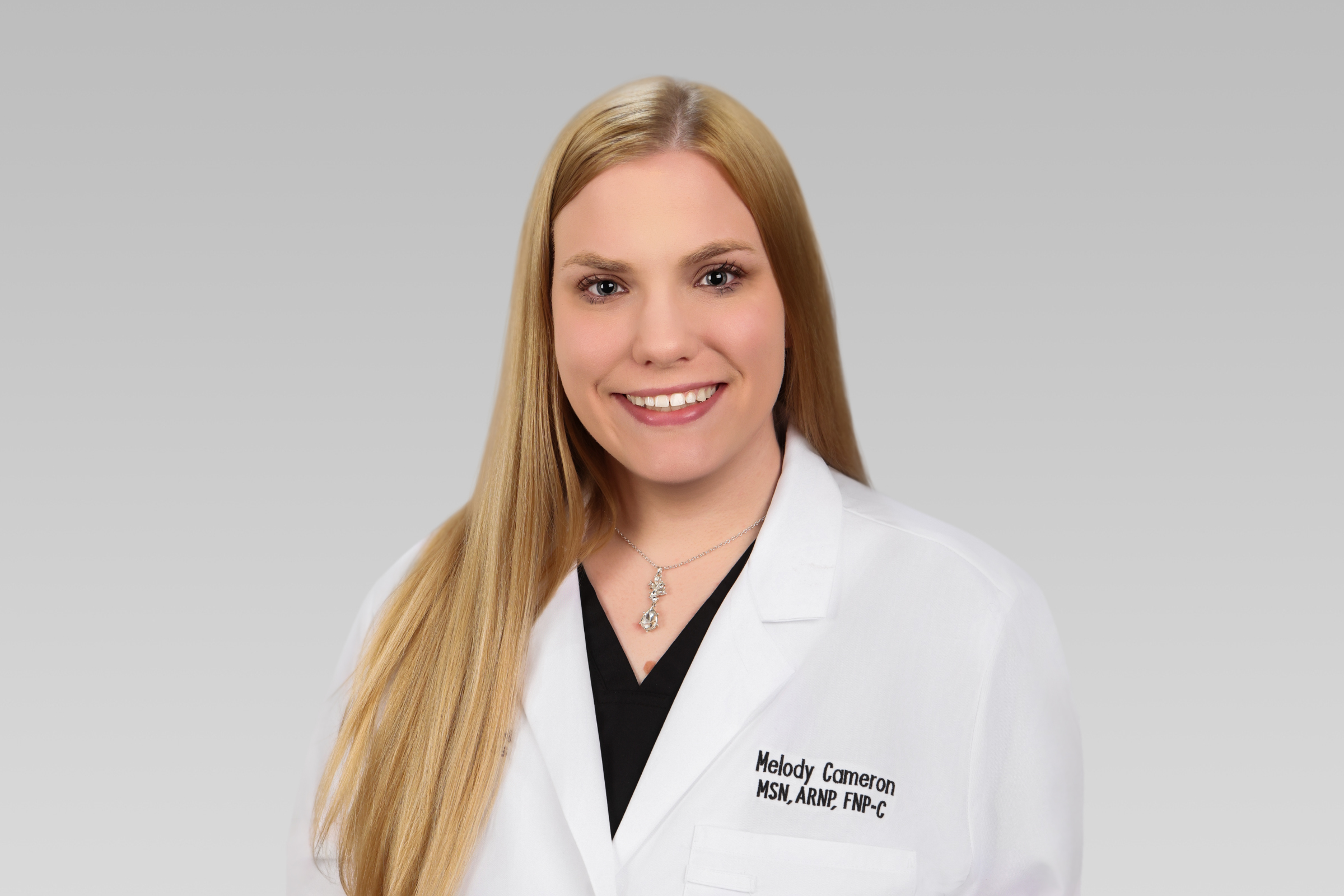 Smiling female healthcare professional in a white lab coat; name Melody Cameron, MSN, ARNP, FNP-C is visible on the coat.